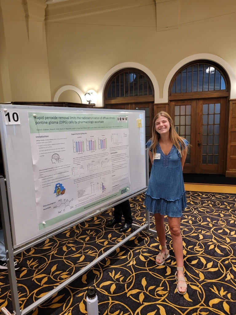 Claire stands next to her poster at the undergraduate research conference.