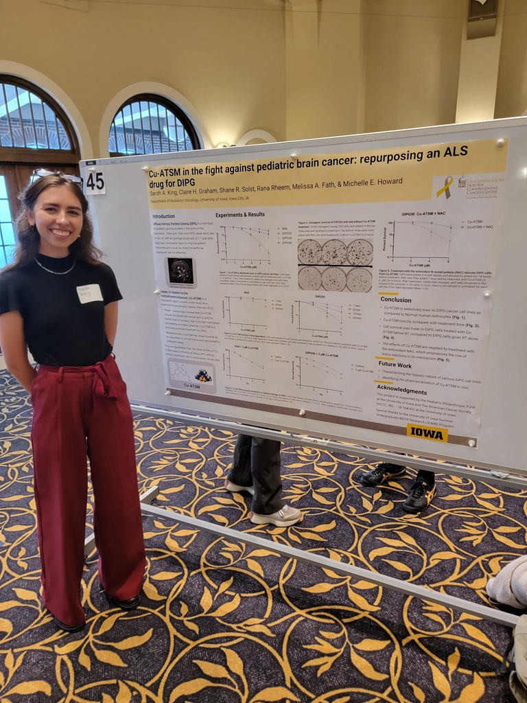 Sarah stands next to her poster at the Undergraduate research conference