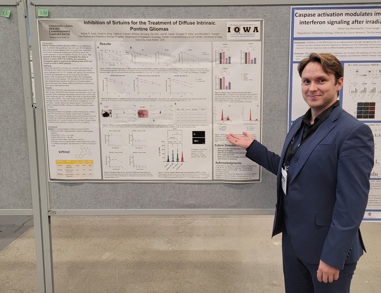 Dr. Shane Solst stands next to his poster at ICRR